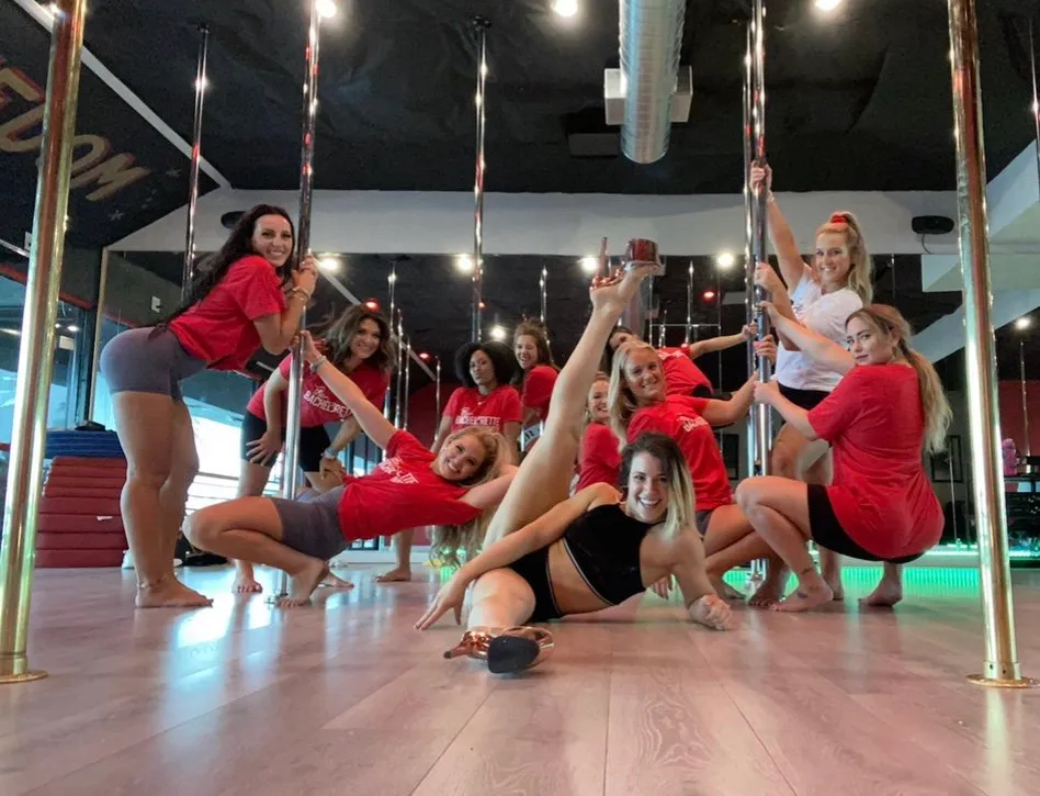 Bachelorette party group posing under the studio's signature red lights at Pole Fitness Studio